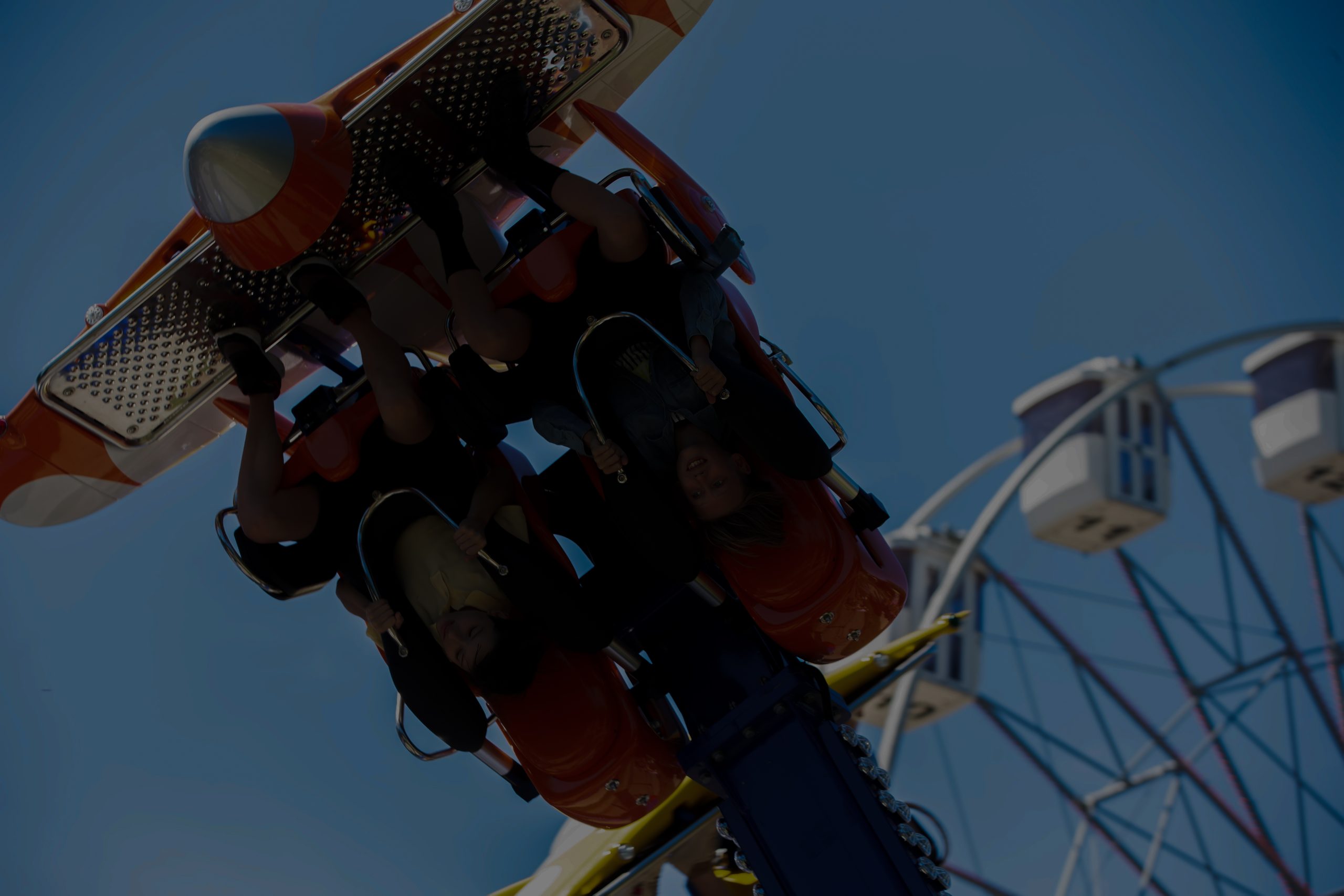Teenagers ride head down on a carousel. Extreme rides in the park.