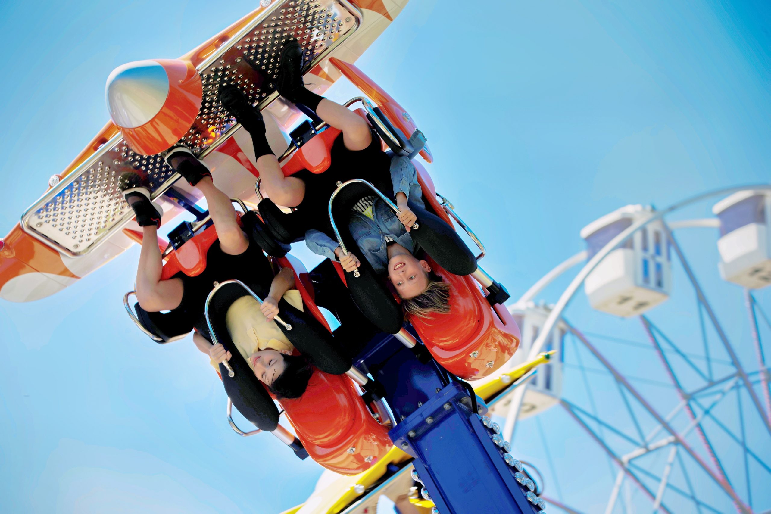 Teenagers ride head down on a carousel. Extreme rides in the park.