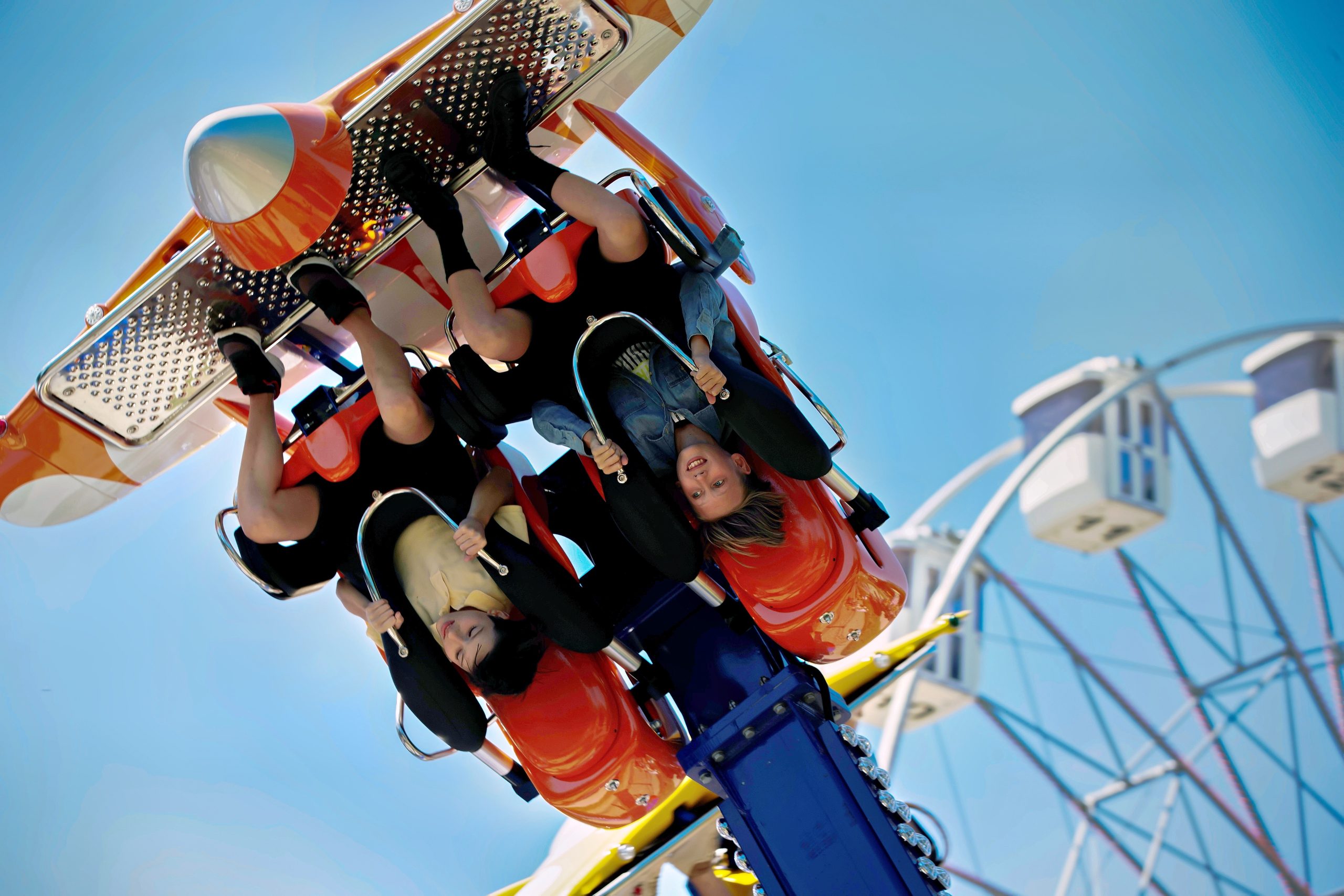 Teenagers ride head down on a carousel. Extreme rides in the park.